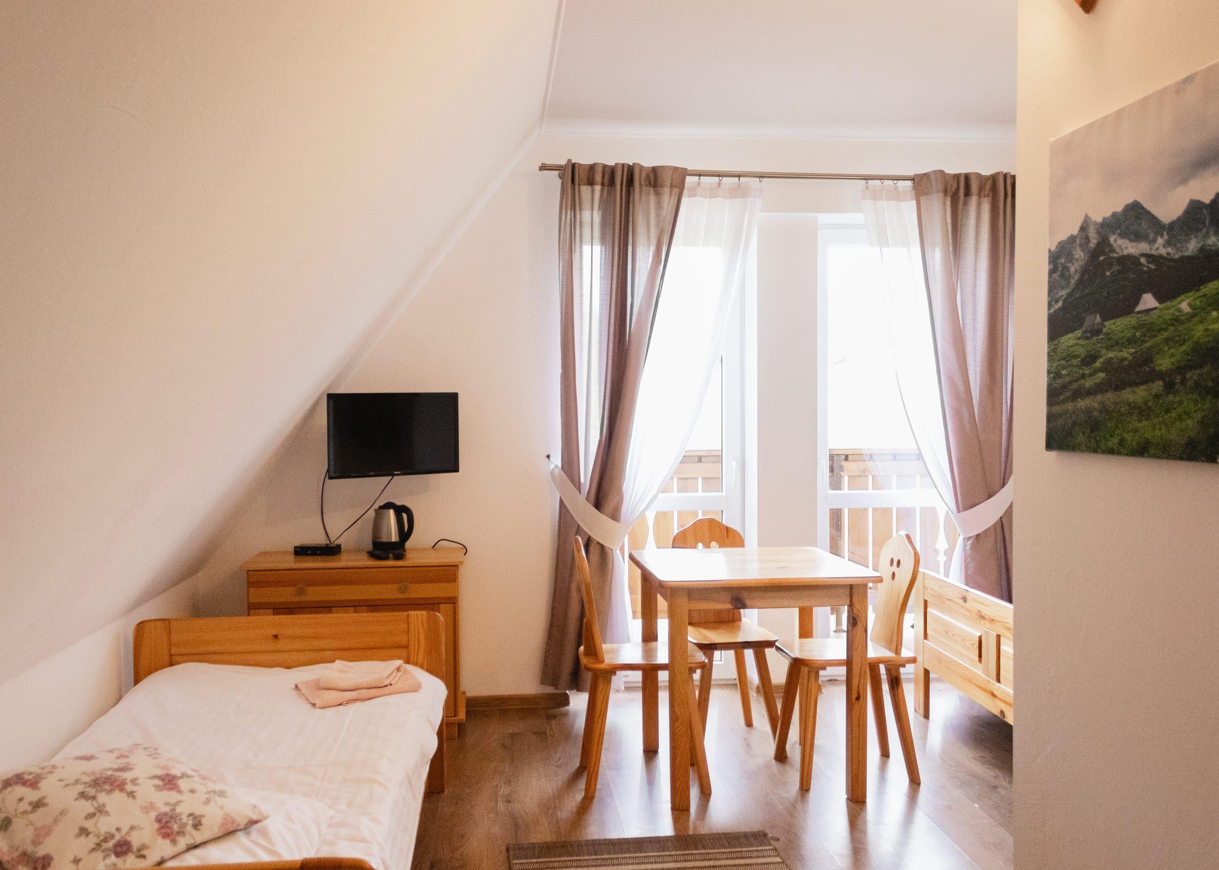 Pokój rodzinny ze stolikiem, telewizorem i wyjściem na balkon